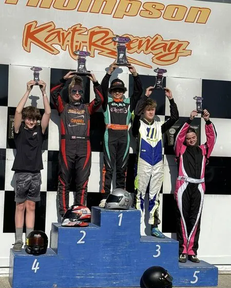 Young kart racers in custom suits celebrating on a podium