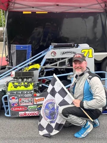 A FervoGear racer with the checkered flag beside his car