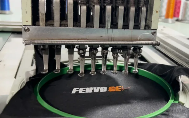An embroidery machine stitching a FervoGear logo